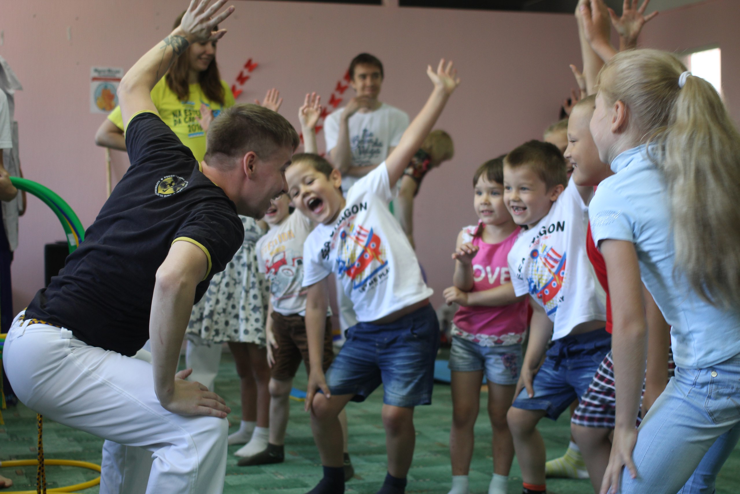 A capoeira class: an instructor and children practising a movement together